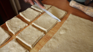 cutting the dough into desired shapes to form individual mandazi pieces.