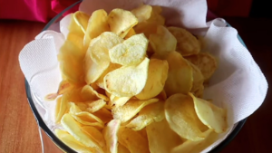 Freshly fried crispy potato crisps just transferred from paper towels to remove excess oil and into a bowl lined with paper towels