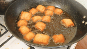 Fry the mini mandazi until golden brown on both sides