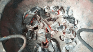A close up look at the few coals in the charcoal stove/ jiko for baking without an oven on the charcoal stove.