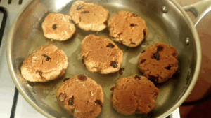 Stovetop banana cookies flipped over in the pan, golden brown and evenly cooked on both sides.