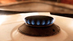 Small gas flame set on low heat for baking no-oven cupcakes in a covered pan.