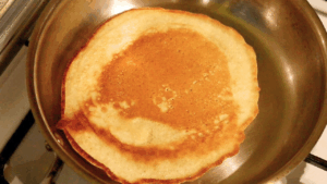 Beautifully browned sourdough pancake on pan, fluffy inside and crisp outside.