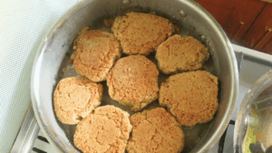 Partially cooked tea scones flipped to the second side in the pan to brown evenly.