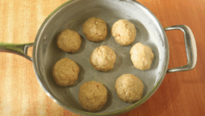 Tea scones shaped into small dough balls arranged in a pan, ready to bake on the stovetop without an oven.