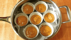 muffin tins in the baking paper-lined pan, with batter ready to bake